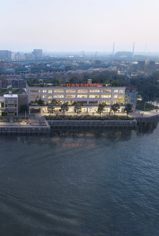 Aerial view of a riverside modern building at dusk, with bright lights and green rooftop,.