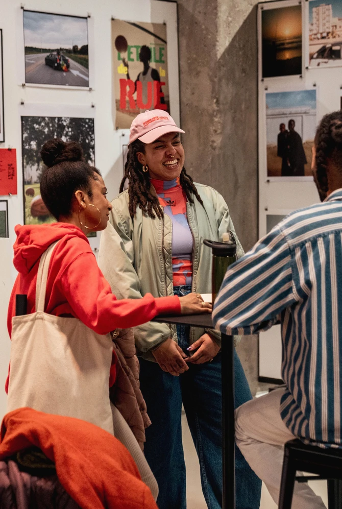Visitors chat beside a display of photography and artwork at the African Food Festival.