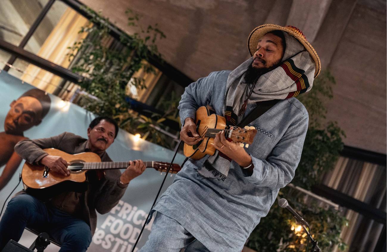 Two musicians play guitars together on stage at the African Food Festival.
