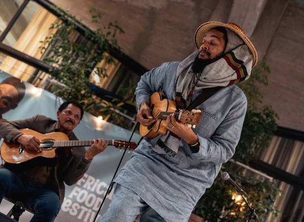 Two musicians play guitars together on stage at the African Food Festival.