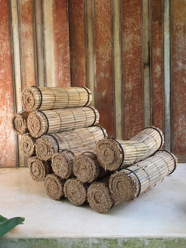 Een fauteuil opgebouwd uit opgerolde bundels riet of stro, strak bijeengebonden en gestapeld tot een