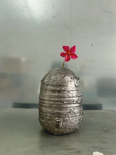 Een fauteuil opgebouwd uit opgerolde bundels riet of stro, strak bijeengebonden en gestapeld tot een