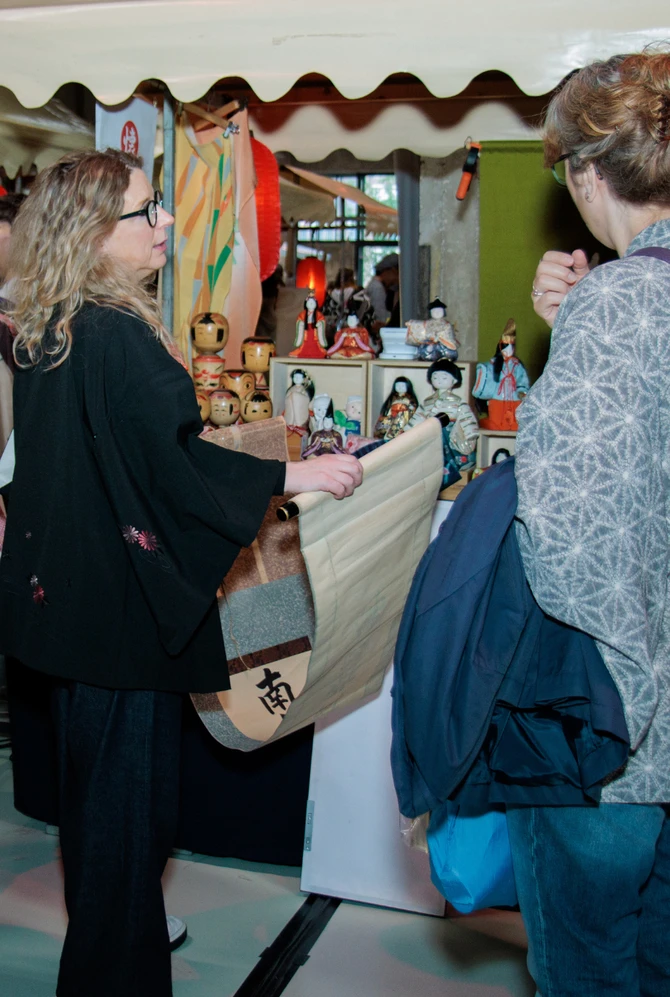 Visitors browse Japanese clothing, dolls and crafts at a market stall during CAMERA JAPAN.