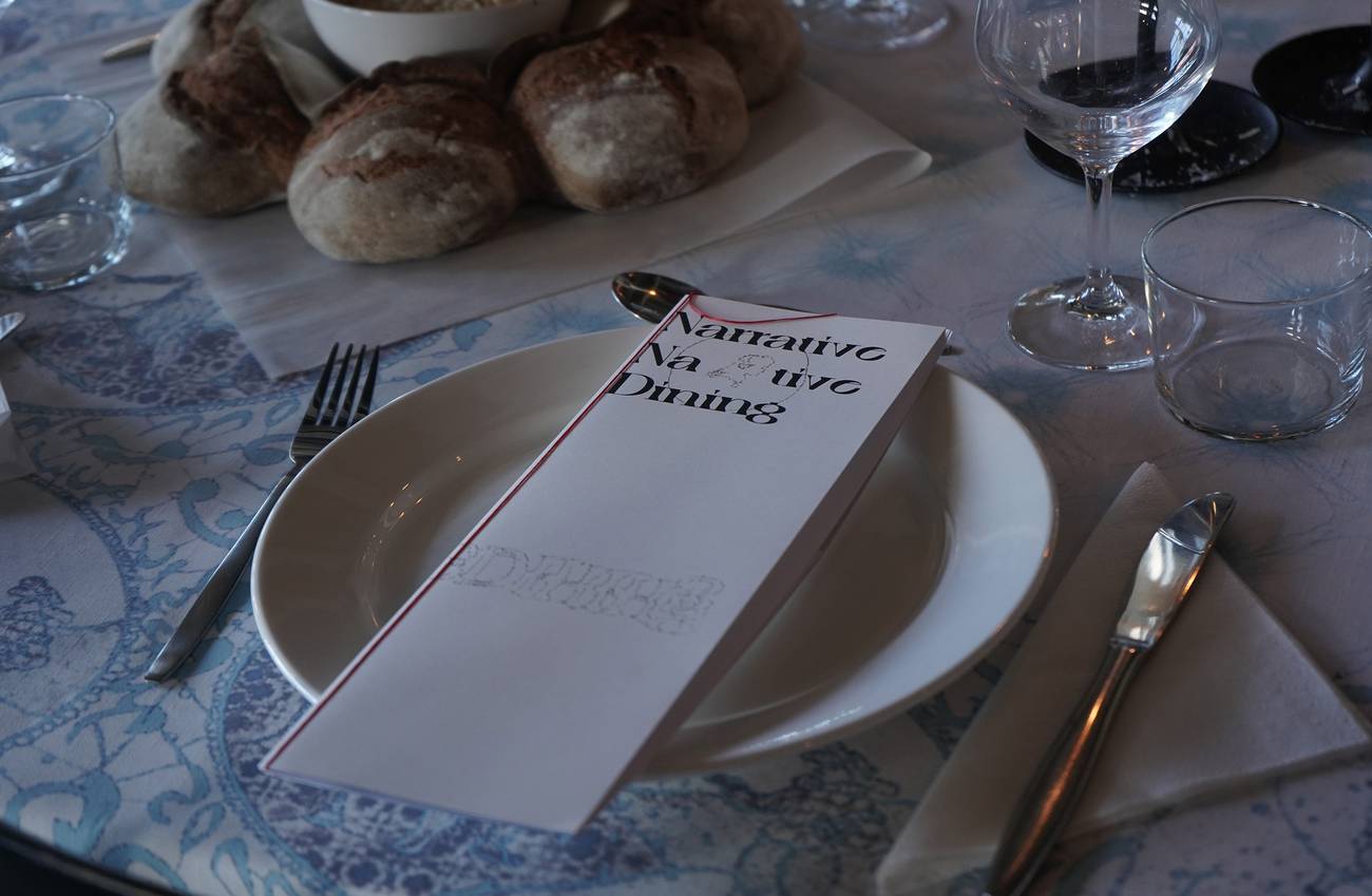 Elegant table setting with a patterned blue dutch tablecloth, menu labeled "Narrative Dining,"