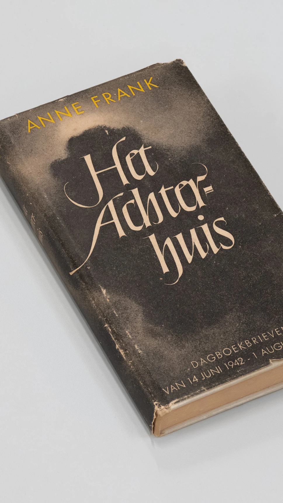 A hardcover book titled "Het Achterhuis" by Anne Frank, featuring a dark cover with gold lettering.