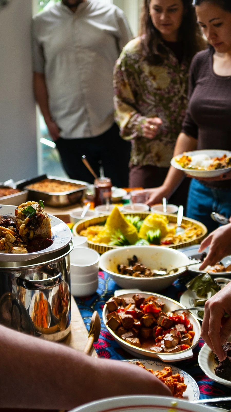 Guests serve themselves a variety of Indonesian dishes from a shared buffet table.