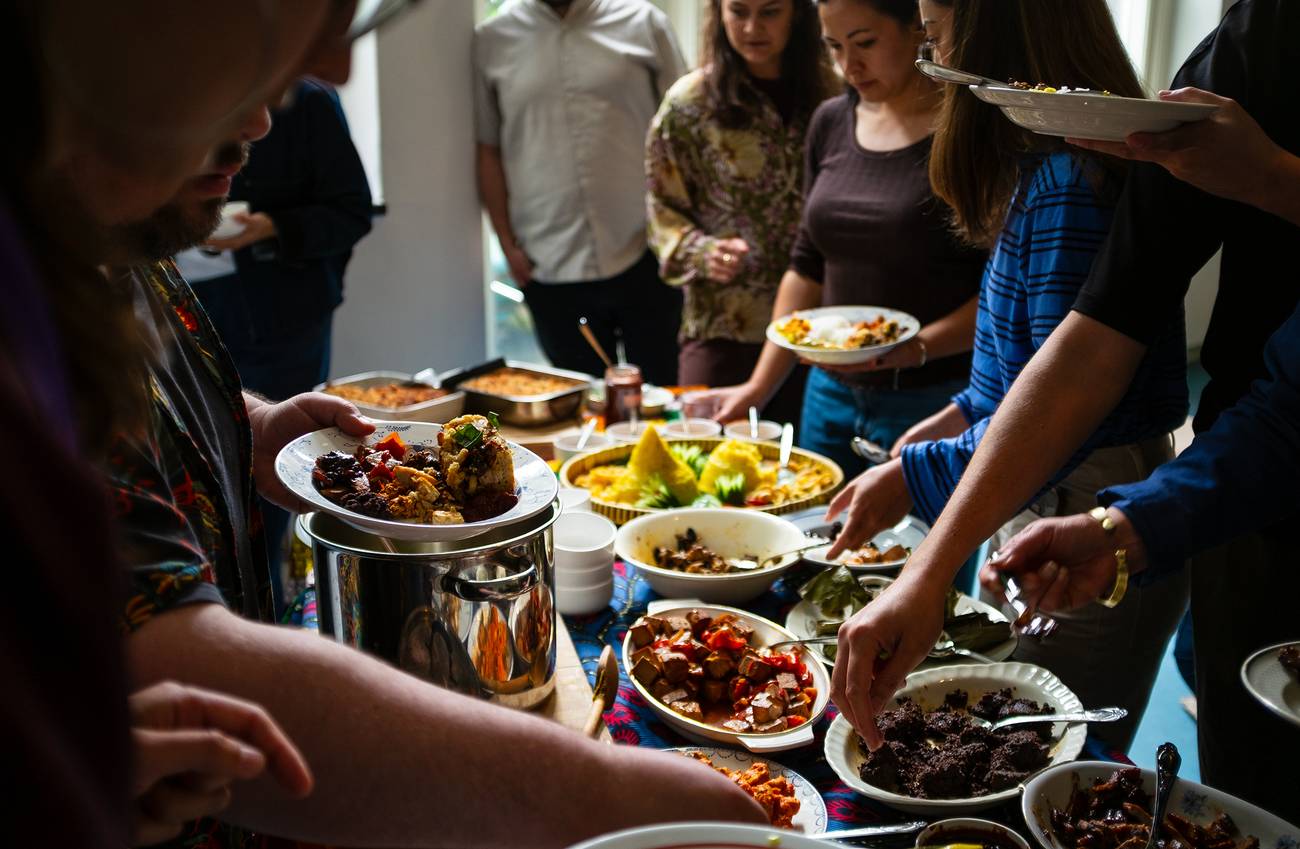 Guests serve themselves a variety of Indonesian dishes from a shared buffet table.