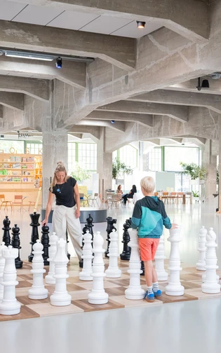 Een moeder en een zoon spelen met een levensgroot schaalspel op Plein