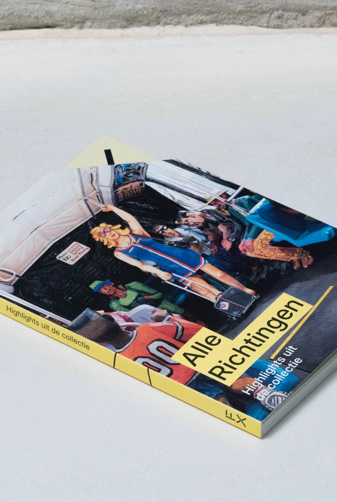 een boek ligt op een neutrale ondergrond, op de cover een foto van het kunstwerk 'the bus'