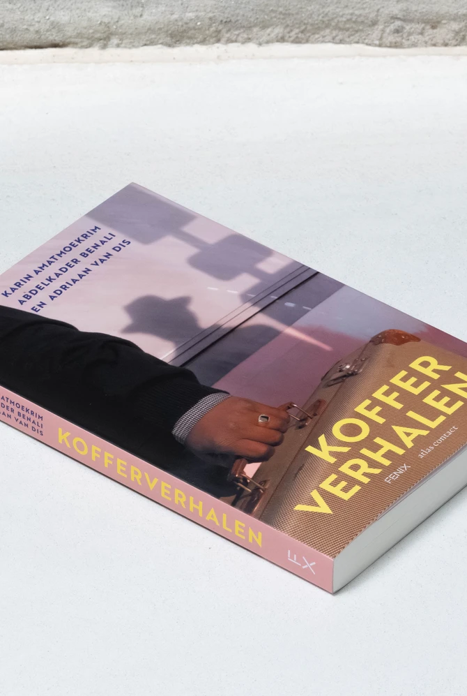 een boek ligt op een neutrale ondergrond, op de cover foto van een koffer