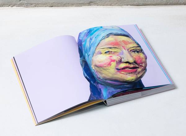 een boek ligt opengeslagen op een neutrale ondergrond, op de pagina een gekleid vrouwelijk gezicht