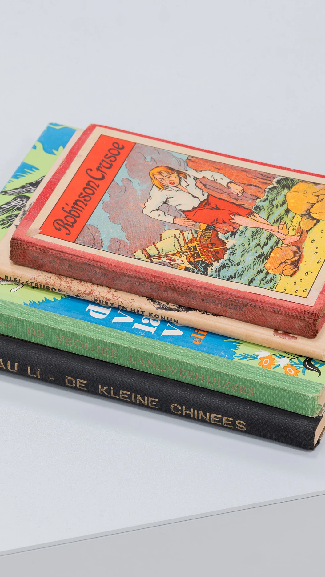 een stapel boeken, waarvan de bovenste titel te lezen is als: Robinson Crusoe