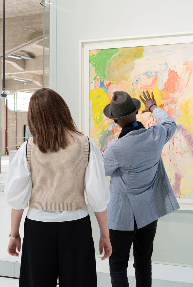 A group of four people stand in an art gallery, observing a colorful abstract painting.