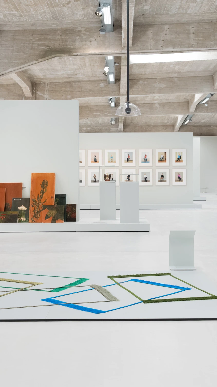 A person reads a folder in a spacious art gallery with a geometric artwork on the floor