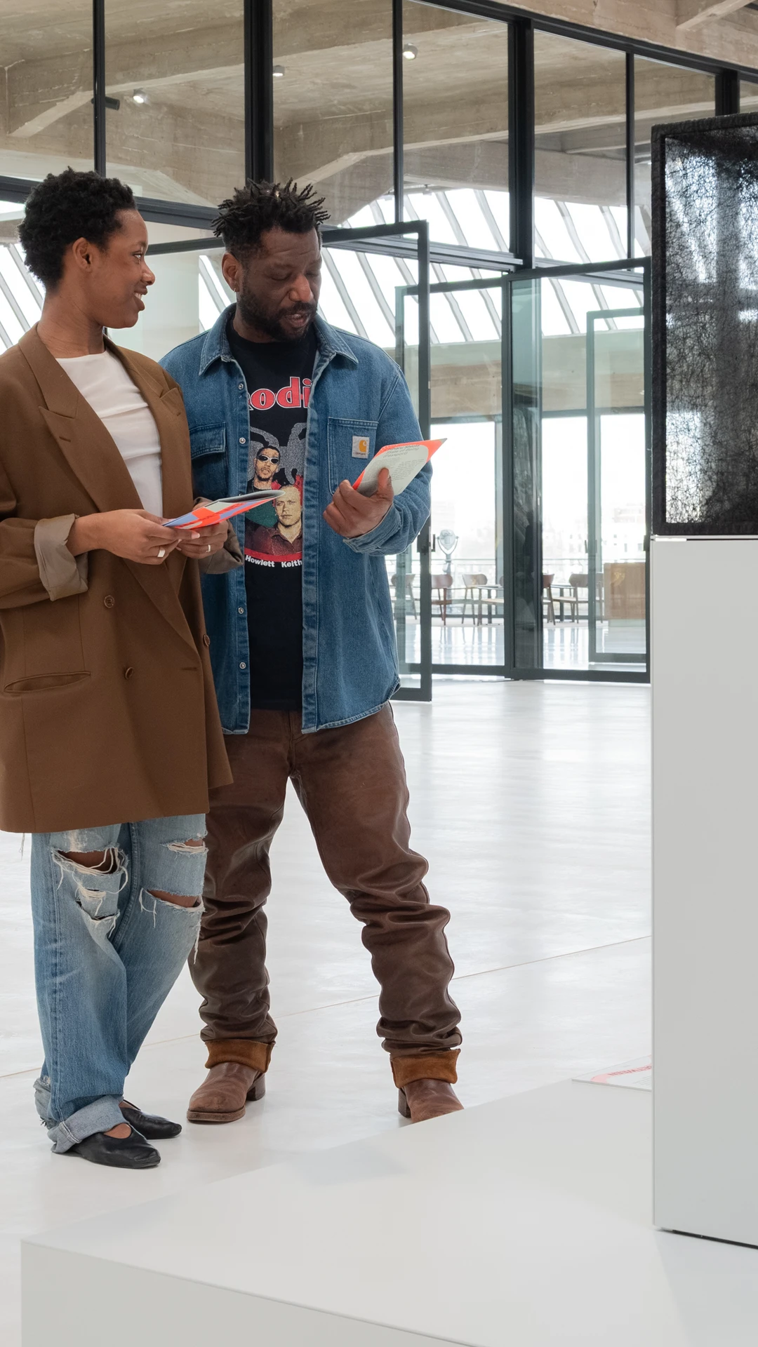 Two people admire a mesh sculpture on a pedestal in a modern art gallery.