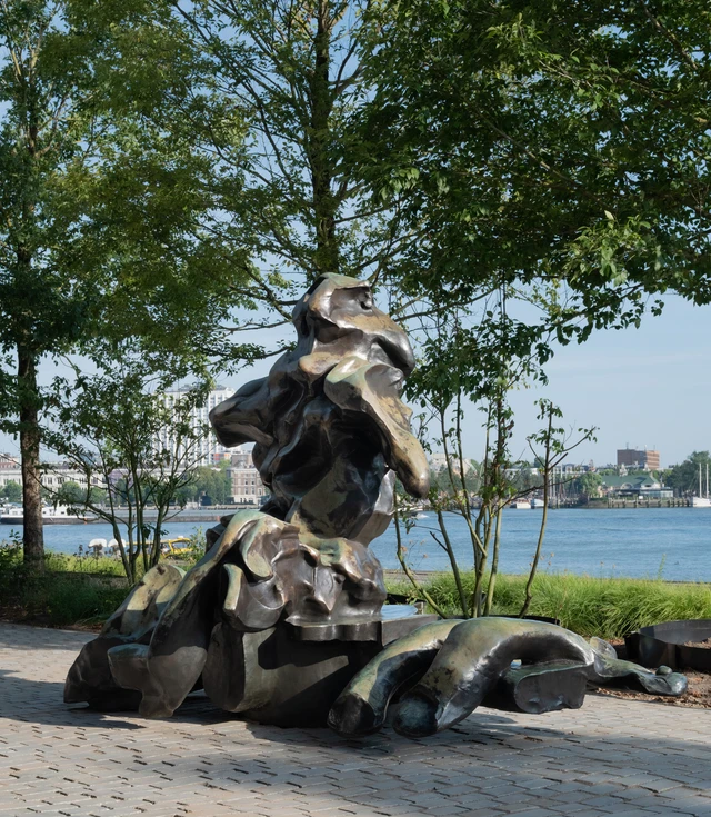 Een groot abstract bronzen beeld staat op de kade voor Fenix.