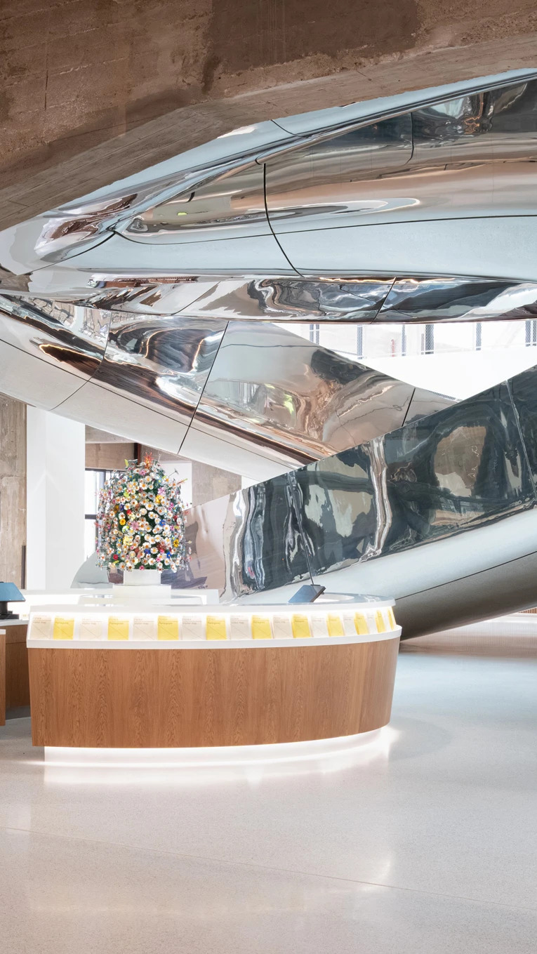 Reception area with a sleek, curved metallic slide above, modern design, neutral colors.