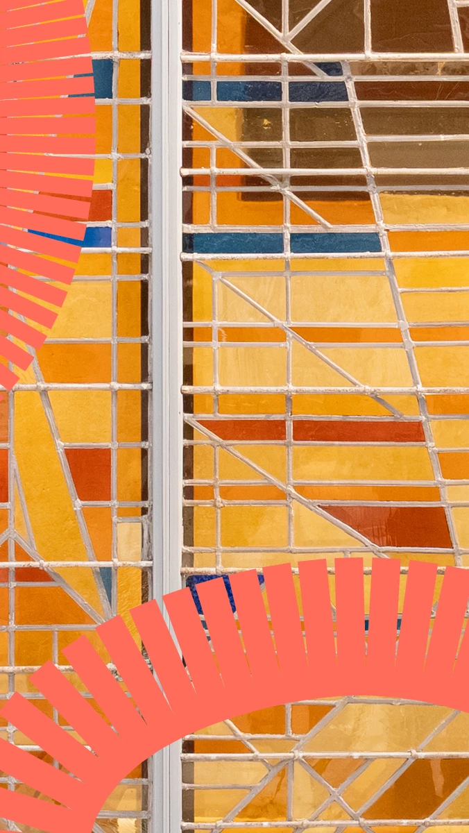 een close-up van glas in lood in geel en oranje, met een grafische kronkelende lijn erover