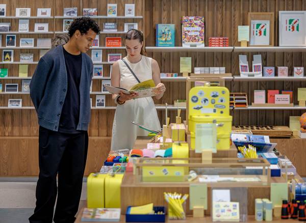 Twee bezoekers staan bij een centrale tafel in de FenixShop en bekijken samen een boek.