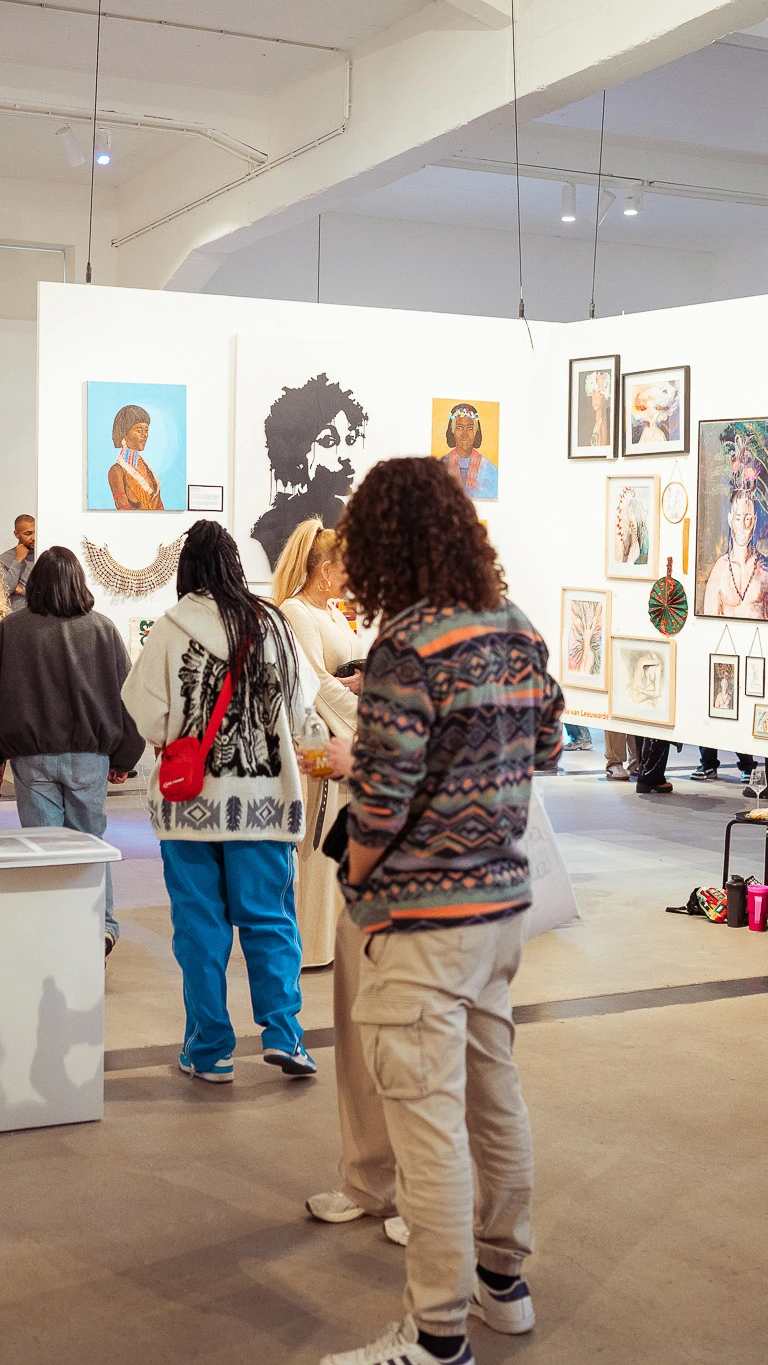 Art gallery with diverse people viewing colourful portraits and abstract art on white walls.