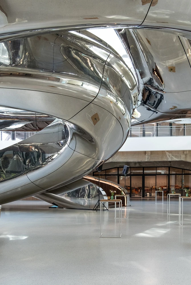 Een grote metalen spiraaltrap binnen een gebouw, met een moderne en industriële uitstraling.