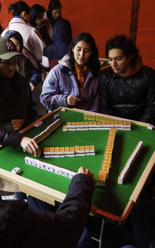een groep mensen speelt Mahjong in een rode tent