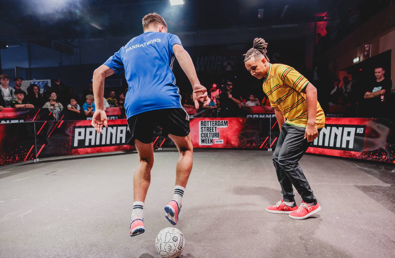 Two street football players face each other over the ball during a panna battle.