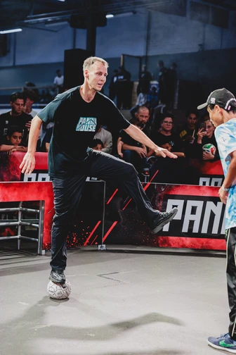 A street football player demonstrates his skills with the ball in front of a watching crowd.