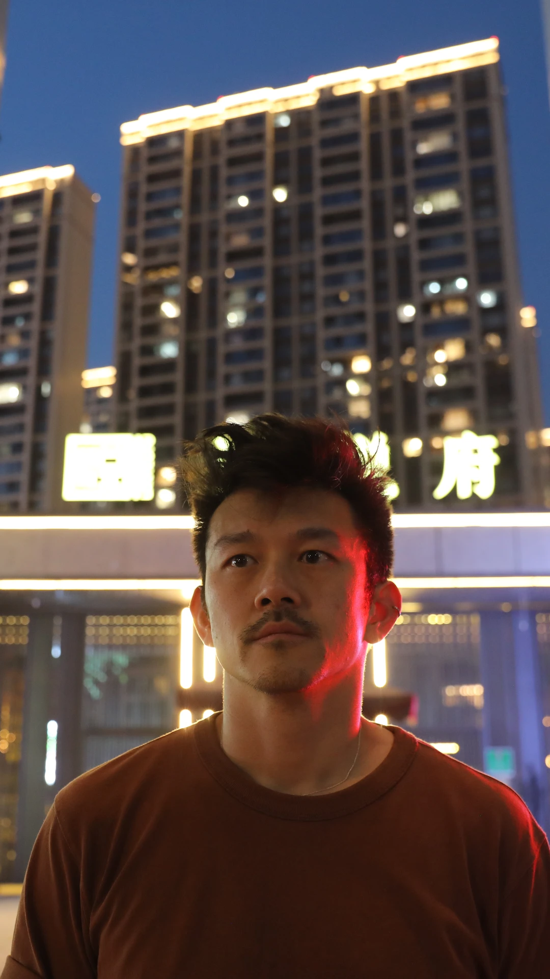 A man standing in the dark in front of a building.