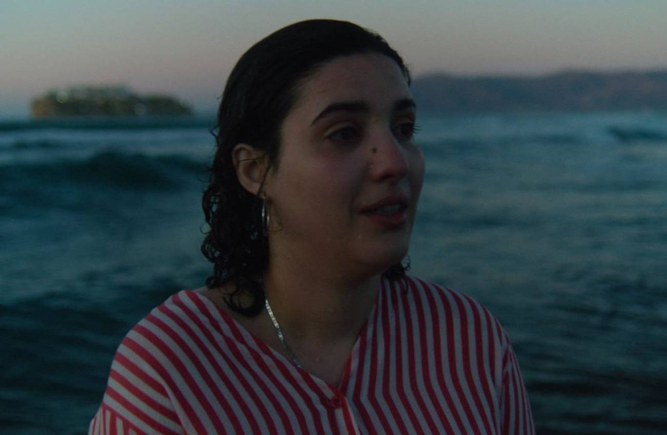 Woman standing in front of the see looking forward