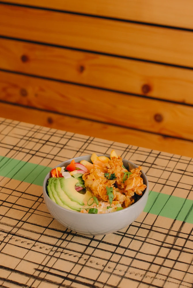 Een kom met verschillende ingredienten, kip, rijst, avocado