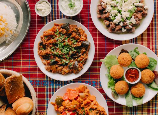 een volle tafel met verschillende gerechten: falafel, aubergine, brood en rijst