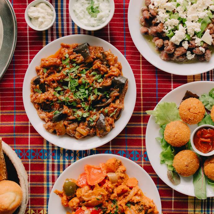 een volle tafel met verschillende gerechten: falafel, aubergine, brood en rijst