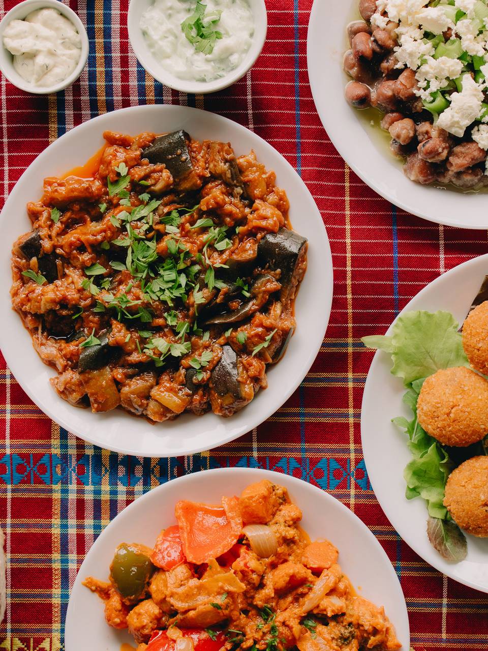 een volle tafel met verschillende gerechten: falafel, aubergine, brood en rijst