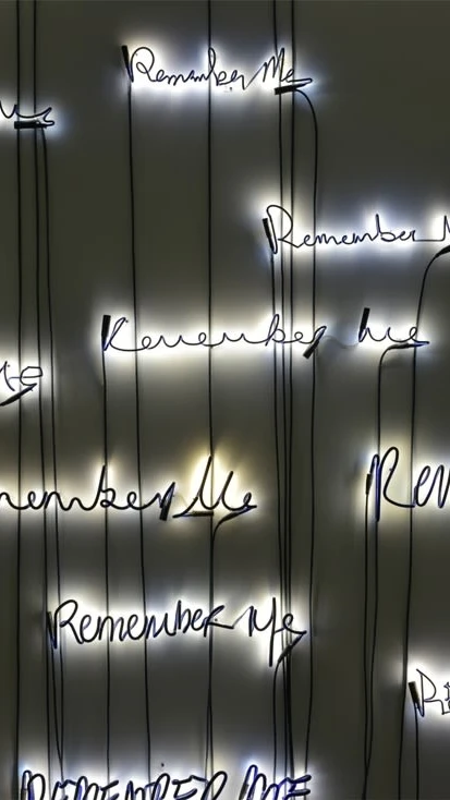 An illuminated installation featuring the words ‘Remember Me’ written repeatedly in different handwr