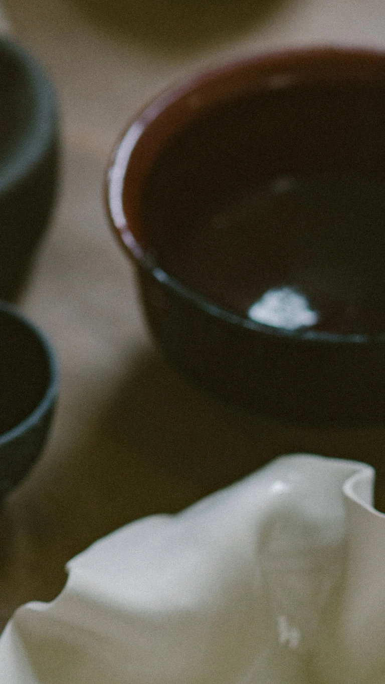 A stack of glazed ceramic plates and bowls in earthy brown, cream and yellow tones.