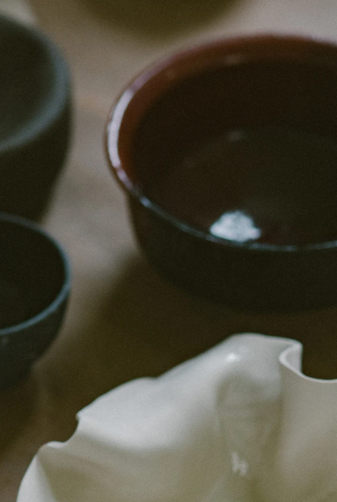 A stack of glazed ceramic plates and bowls in earthy brown, cream and yellow tones.