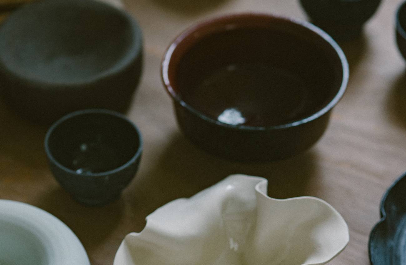 A stack of glazed ceramic plates and bowls in earthy brown, cream and yellow tones.