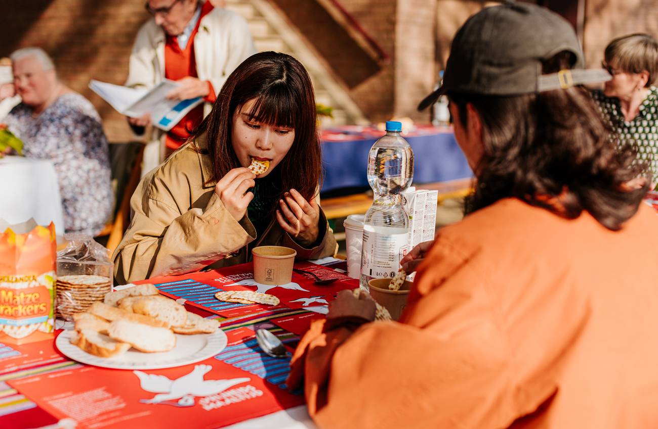 Two people sit at an outdoor table enjoying a casual meal with crackers and bread.