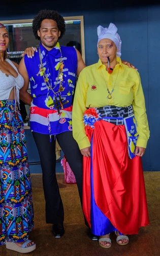 Three people pose together in colourful Cabo Verdean clothing during a cultural event at Fenix.