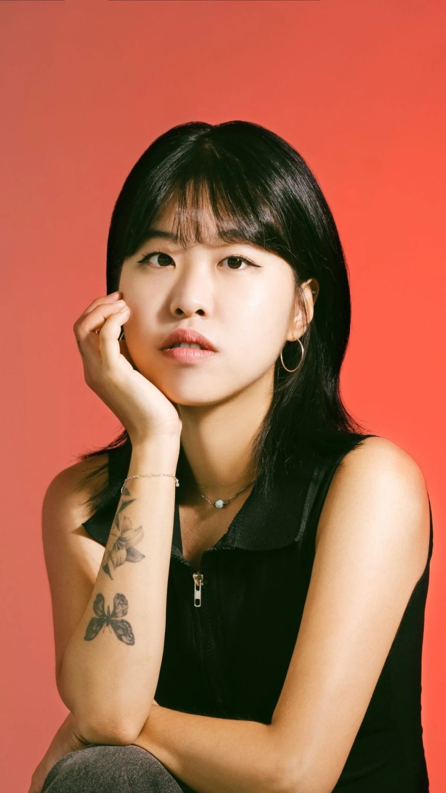 Young woman with long black hair wearing hoop earrings and a black sleeveless top