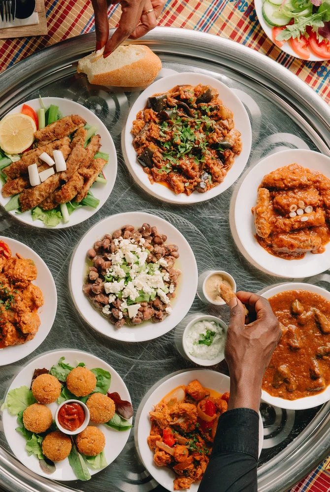 alt text 1 regel engels People sharing Sudanese dishes served on a large traditional tray.