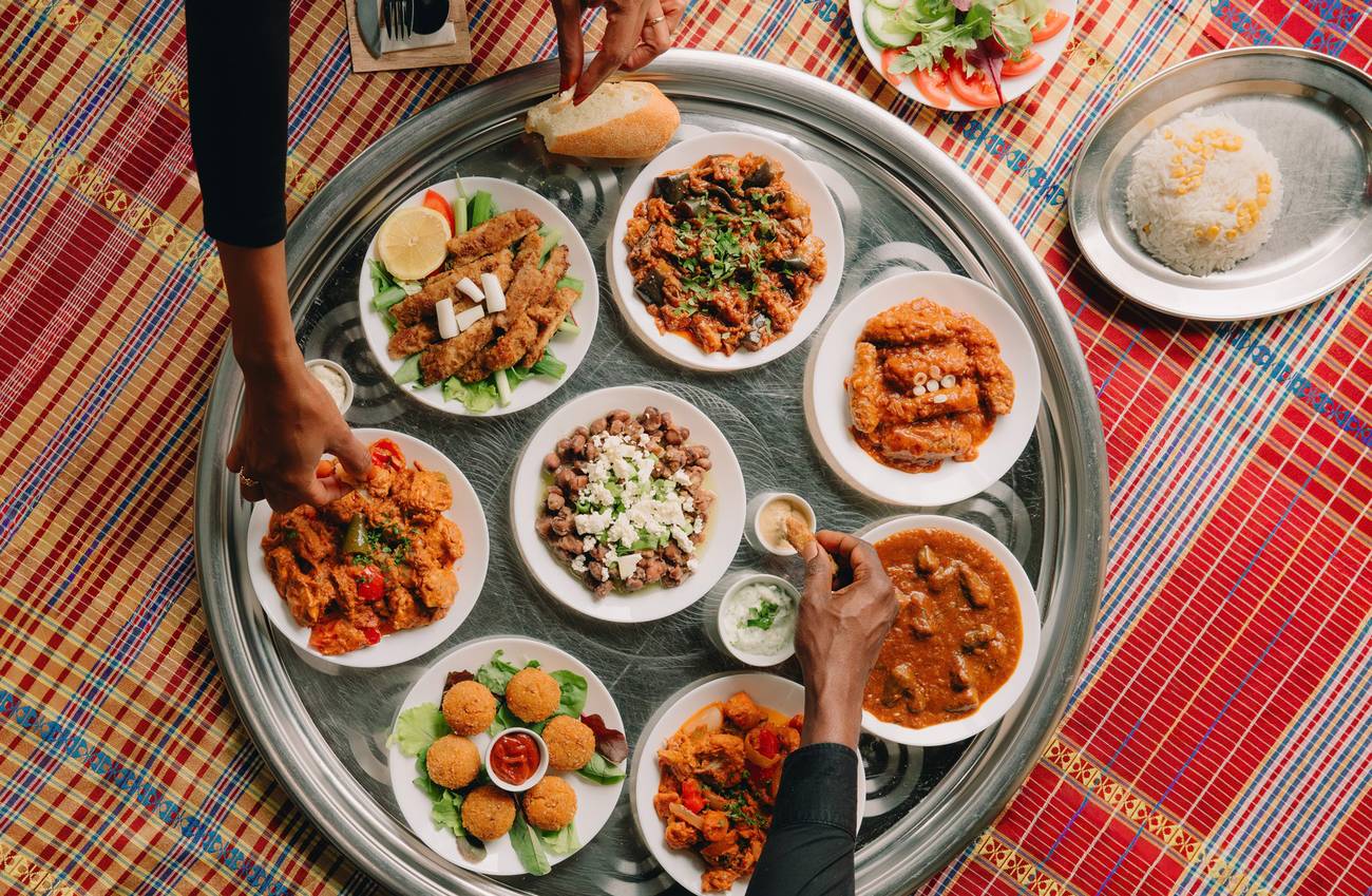 alt text 1 regel engels People sharing Sudanese dishes served on a large traditional tray.