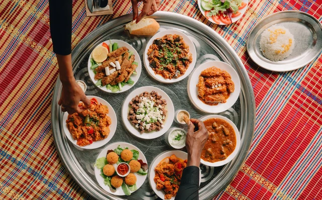 alt text 1 regel engels People sharing Sudanese dishes served on a large traditional tray.