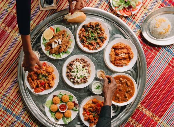 alt text 1 regel engels People sharing Sudanese dishes served on a large traditional tray.