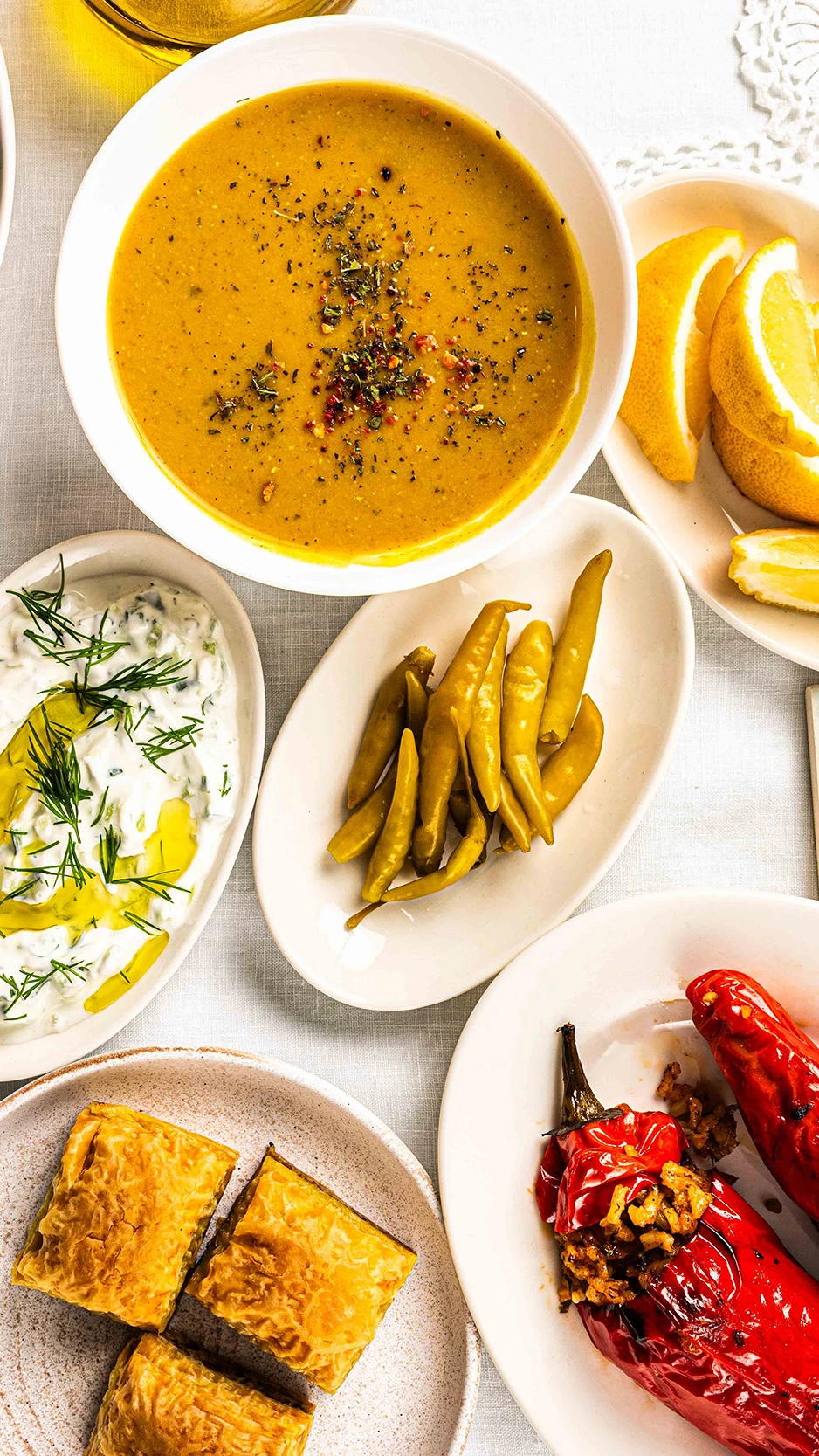A top view of a table filled with various dishes, including stuffed red peppers, lentil soup, a sala