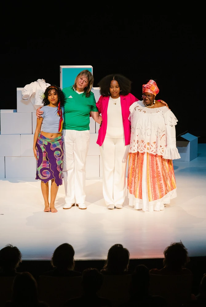 Vier vrouwen van verschillende afkomsten op een podium tijdens een voorstelling in het theater