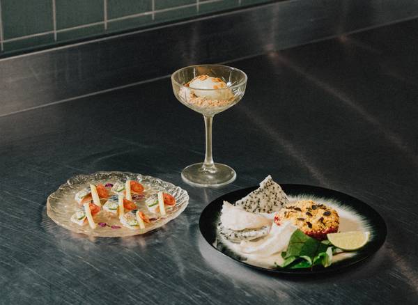 Elegant dish trio on a stainless-steel counter: mackerel, dessert in a glass, and tartar.