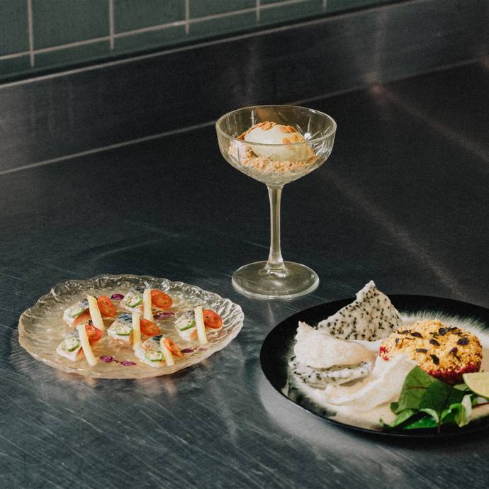 Elegant dish trio on a stainless-steel counter: mackerel, dessert in a glass, and tartar.