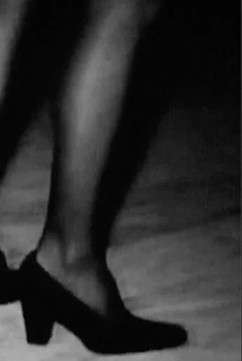 zwart-wit still uit een film, waarop afgesneden twee vrouwelijke benen te zien zijn.